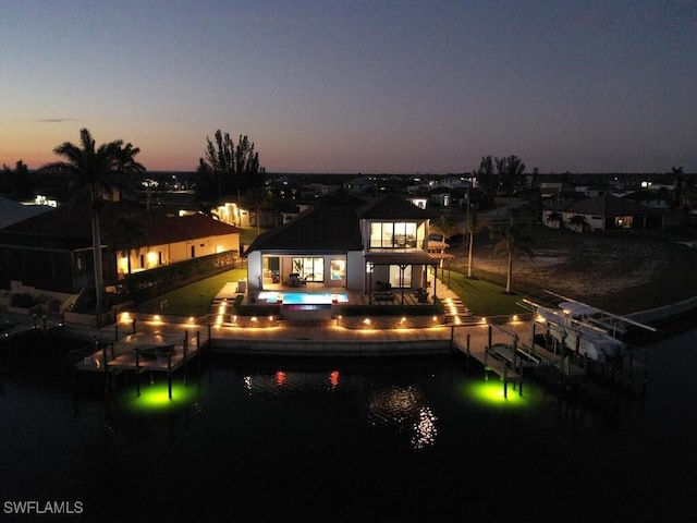 back house at dusk with a patio and a water view