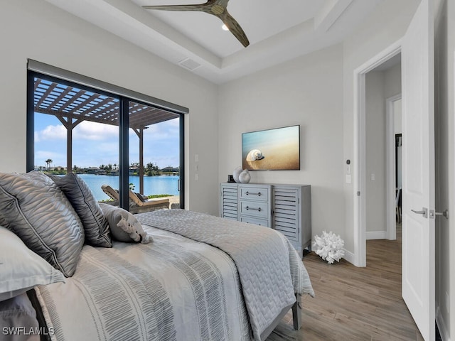 bedroom with a tray ceiling, wood-type flooring, ceiling fan, and access to outside