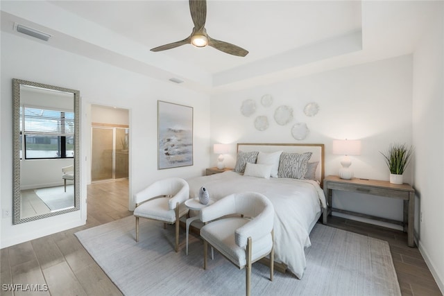 bedroom with ensuite bath, ceiling fan, and a tray ceiling