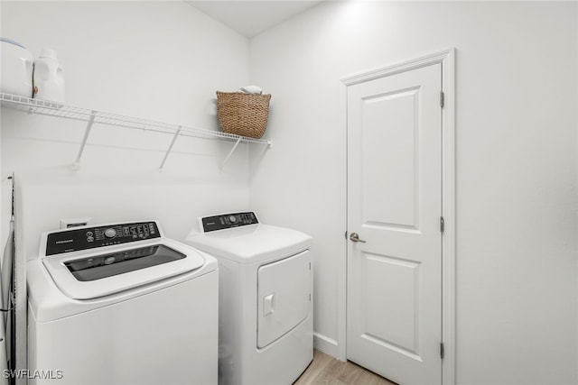 clothes washing area with light wood-type flooring and independent washer and dryer