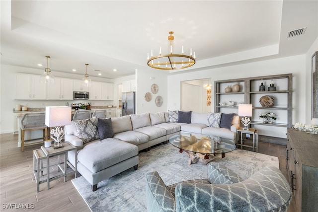 living room with an inviting chandelier and a tray ceiling