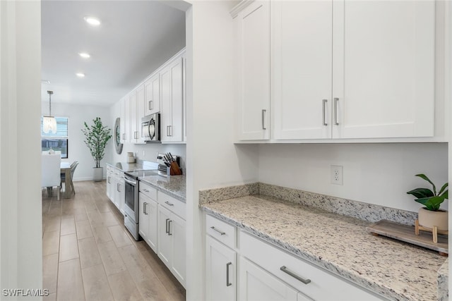 kitchen featuring light hardwood / wood-style flooring, hanging light fixtures, stainless steel appliances, light stone counters, and white cabinets