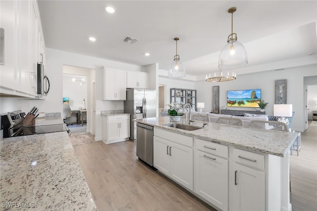 kitchen with sink, a center island with sink, appliances with stainless steel finishes, pendant lighting, and white cabinets