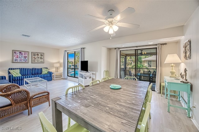 dining room with ceiling fan, light wood-type flooring, and a textured ceiling