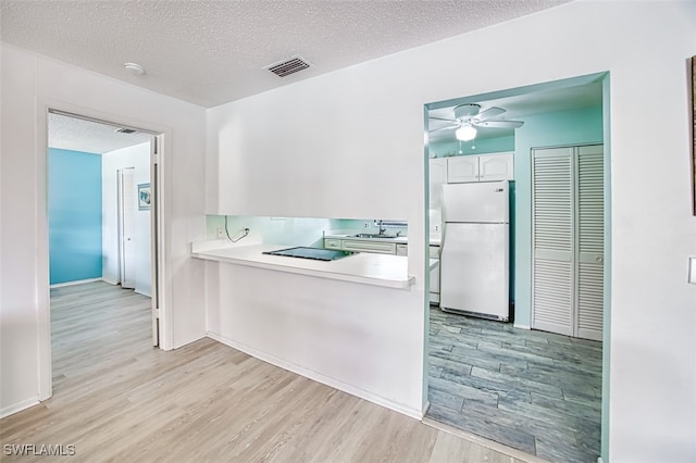 kitchen featuring sink, white cabinetry, white refrigerator, kitchen peninsula, and light hardwood / wood-style floors