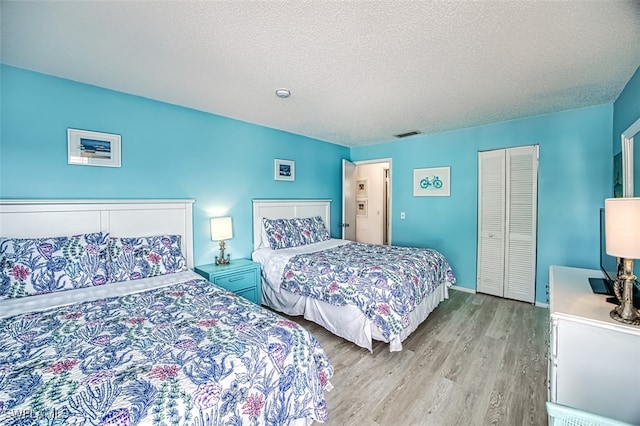 bedroom featuring light hardwood / wood-style floors, a closet, and a textured ceiling