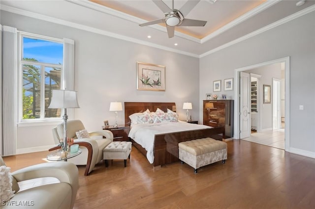 bedroom with a raised ceiling, ornamental molding, ceiling fan, and light wood-type flooring