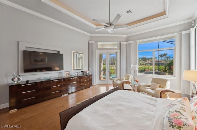 bedroom with french doors, crown molding, a raised ceiling, access to exterior, and hardwood / wood-style floors