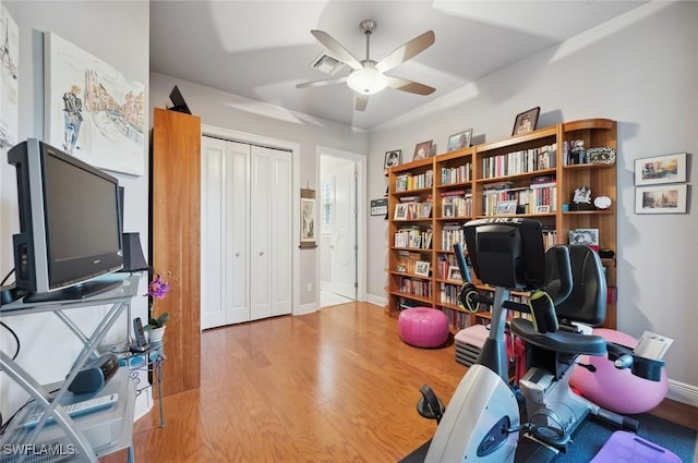 workout room with ceiling fan and light hardwood / wood-style floors