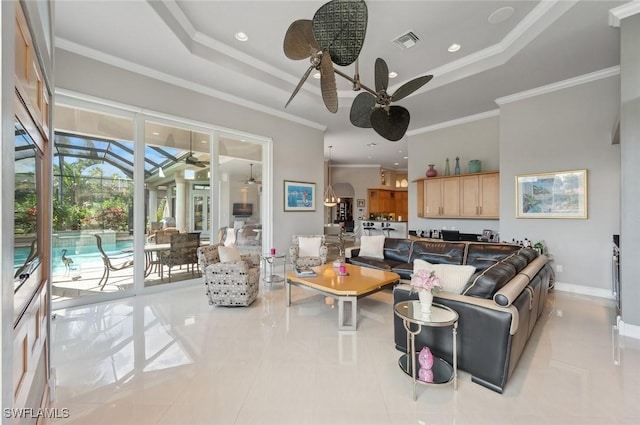 tiled living room featuring ceiling fan, ornamental molding, and a tray ceiling