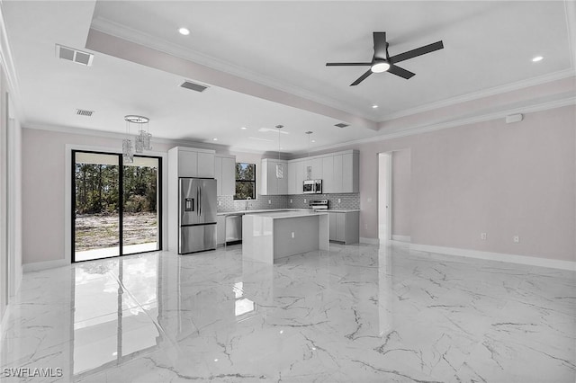 kitchen featuring tasteful backsplash, hanging light fixtures, ornamental molding, a kitchen island, and stainless steel appliances