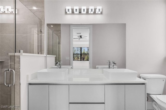 bathroom featuring a shower with door, vanity, ceiling fan, and toilet