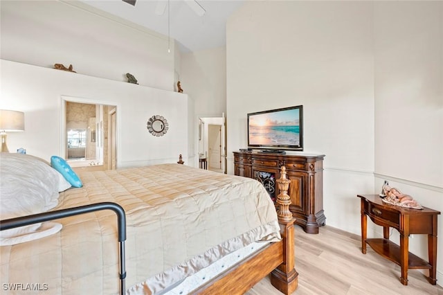 bedroom with light wood finished floors, a high ceiling, and a ceiling fan