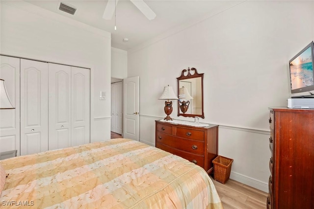 bedroom featuring crown molding, ceiling fan, light wood-type flooring, and a closet