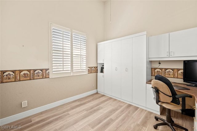 office with a high ceiling and light wood-type flooring