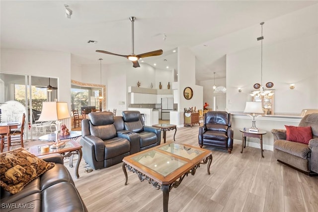 living room with ceiling fan with notable chandelier, light hardwood / wood-style flooring, and high vaulted ceiling