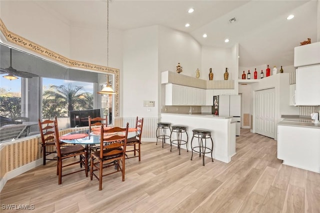 dining room featuring recessed lighting, visible vents, a towering ceiling, and light wood finished floors