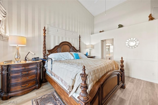 bedroom with connected bathroom, high vaulted ceiling, and light hardwood / wood-style flooring