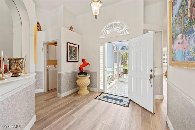 foyer with separate washer and dryer, a towering ceiling, and light hardwood / wood-style floors