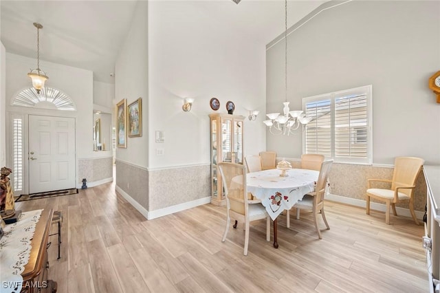 dining area featuring light hardwood / wood-style flooring, high vaulted ceiling, and a chandelier