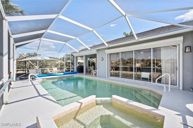 view of pool featuring an in ground hot tub, a patio area, and glass enclosure