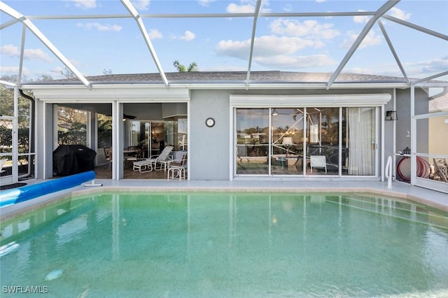 rear view of property featuring a patio, glass enclosure, and an outdoor pool