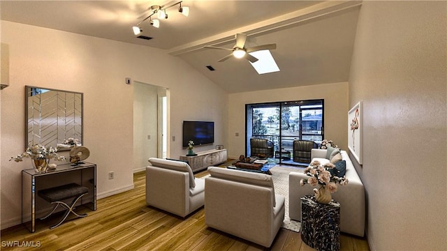 living room with hardwood / wood-style flooring, ceiling fan, and vaulted ceiling with skylight