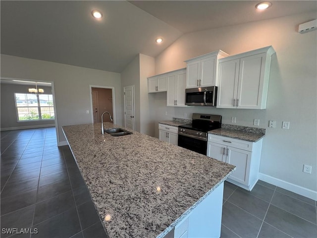 kitchen featuring white cabinets, appliances with stainless steel finishes, a sink, baseboards, and vaulted ceiling