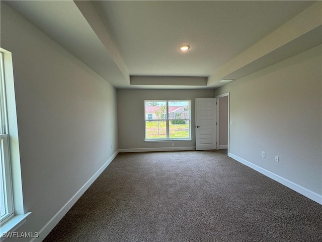 spare room featuring recessed lighting, baseboards, a tray ceiling, and dark colored carpet