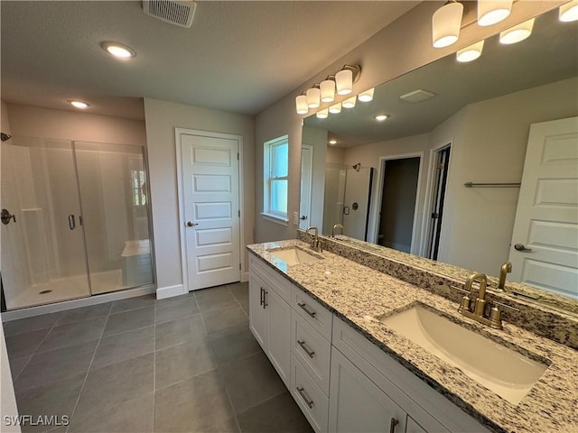 bathroom with double vanity, visible vents, a sink, and a stall shower