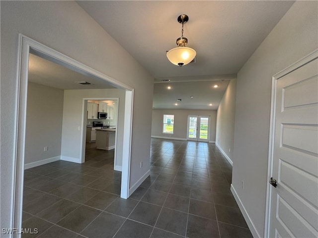 corridor featuring dark tile patterned floors and baseboards