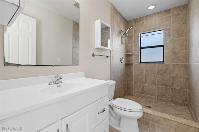 bathroom with vanity, toilet, and tiled shower