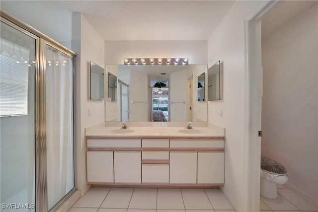 bathroom with vanity, toilet, a shower with shower door, and tile patterned flooring