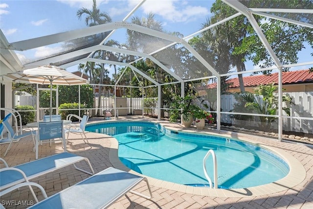 view of pool with glass enclosure and a patio area