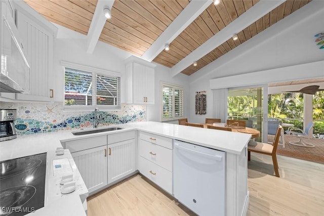 kitchen with sink, white dishwasher, kitchen peninsula, decorative backsplash, and white cabinets