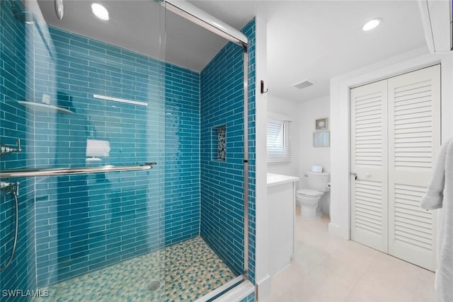 bathroom with tile patterned flooring, vanity, a shower with shower door, and toilet