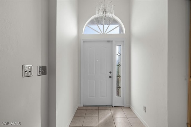 tiled entryway with a notable chandelier