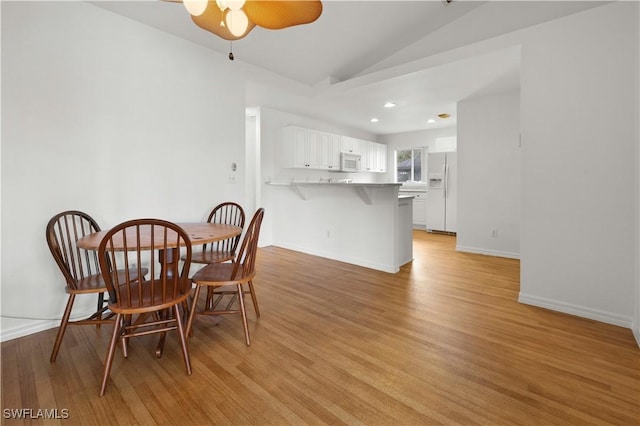 dining room with vaulted ceiling, ceiling fan, and light hardwood / wood-style floors