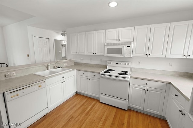 kitchen with white cabinetry, sink, kitchen peninsula, white appliances, and light hardwood / wood-style flooring