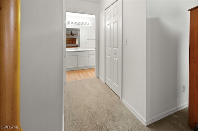 hallway with sink and light carpet