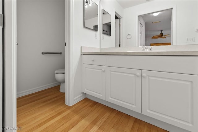 bathroom featuring ceiling fan, wood-type flooring, toilet, and vanity