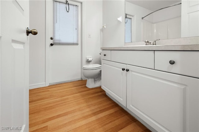 bathroom featuring hardwood / wood-style flooring, vanity, walk in shower, and toilet