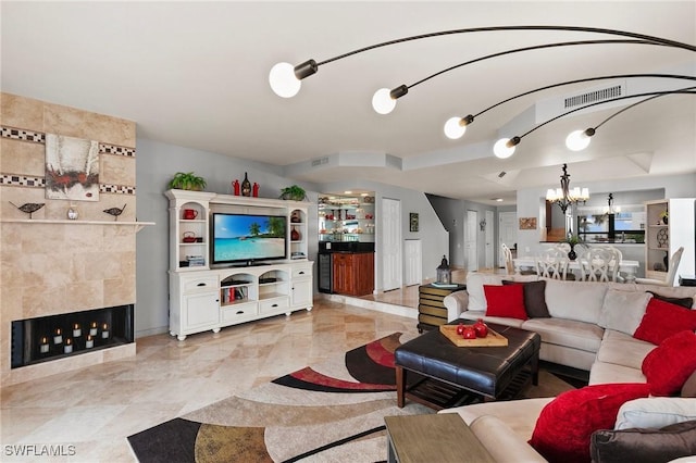 living room with a notable chandelier and a tile fireplace