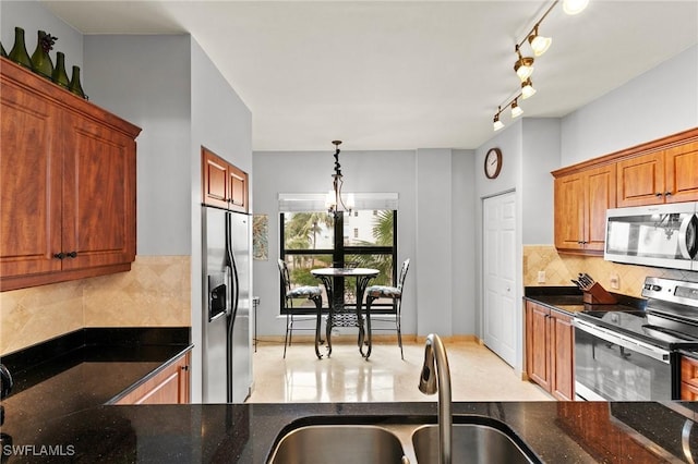 kitchen with sink, appliances with stainless steel finishes, hanging light fixtures, decorative backsplash, and dark stone counters