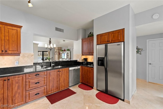 kitchen featuring tasteful backsplash, sink, hanging light fixtures, stainless steel appliances, and an inviting chandelier