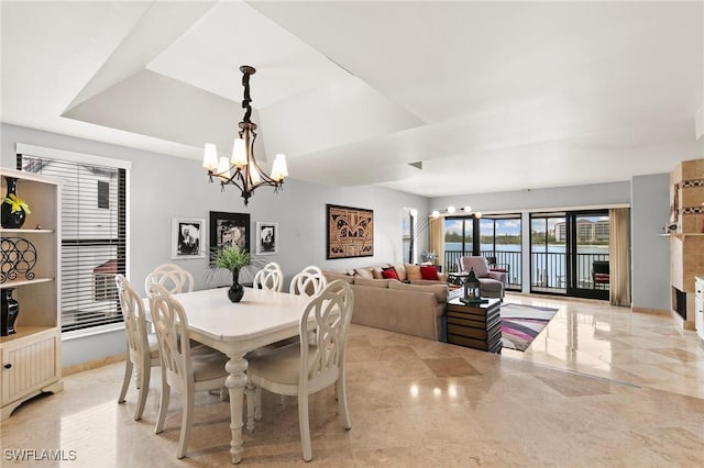 dining area with a raised ceiling and a chandelier