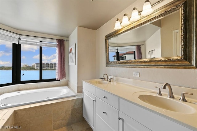 bathroom featuring a relaxing tiled tub, vanity, tile patterned floors, and a water view