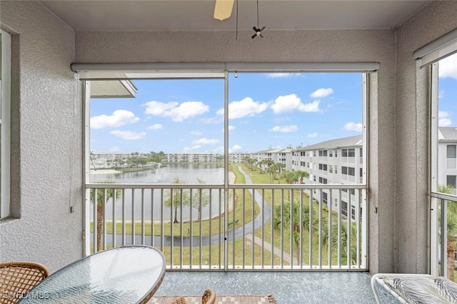 sunroom with a water view and ceiling fan