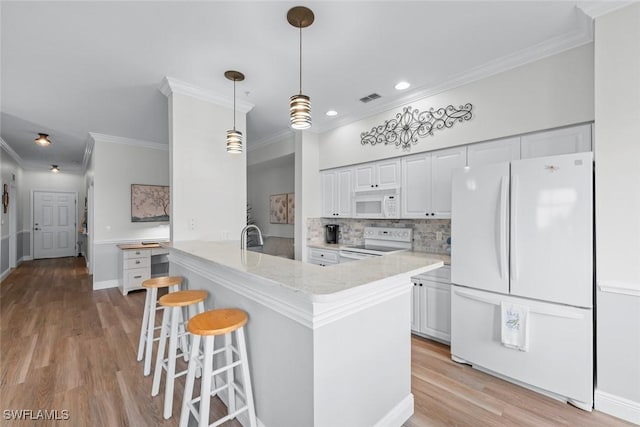 kitchen featuring white cabinets, decorative backsplash, hanging light fixtures, kitchen peninsula, and white appliances