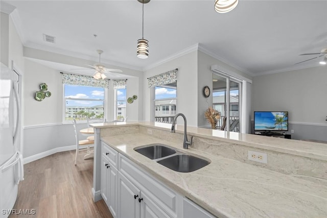 kitchen with white cabinetry, sink, white refrigerator, light stone counters, and crown molding